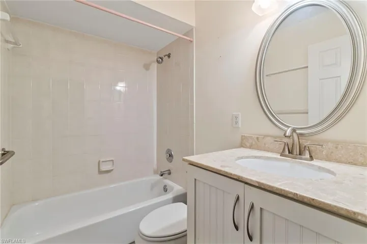 Full bathroom with tiled shower / bath, vanity, and toilet