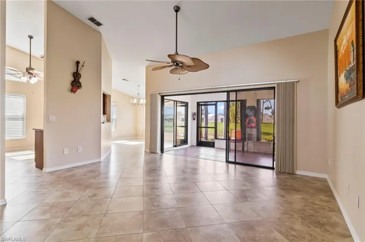Living room featuring light tile patterned floors, ceiling fan with notable chandelier, and a healthy amount of sunlight