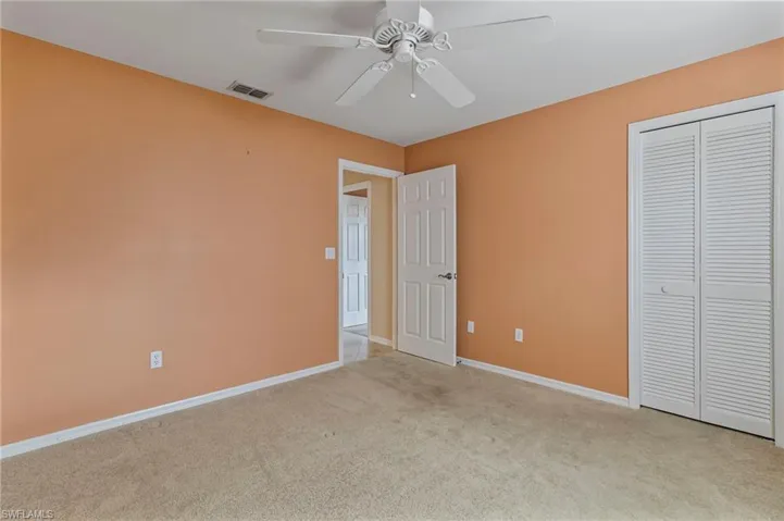 Guest bedroom featuring light colored carpet, ceiling fan, and a closet