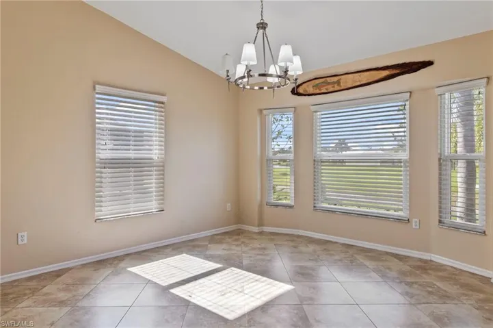 Dining room with vaulted ceiling, plenty of natural light, light tile patterned flooring, and a chandelier