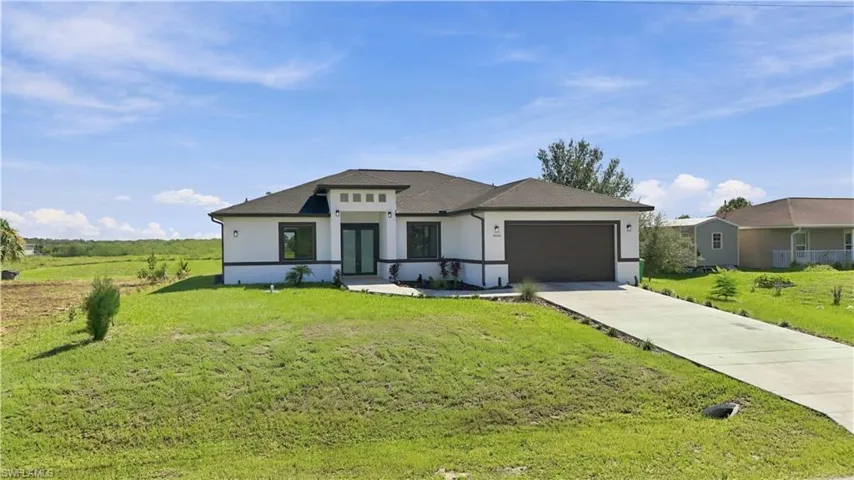Contemporary stucco exterior with dark trim accents, double-door entry, a two-car garage, and an extended concrete driveway