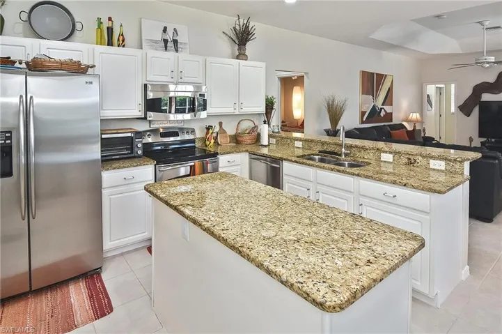 Kitchen featuring a peninsula, stainless steel appliances, white cabinetry, and open floor plan