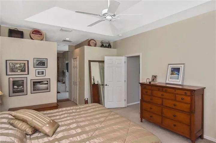 Bedroom with light colored carpet, a closet, ensuite bath, and ceiling fan