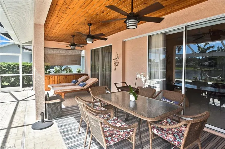 View of patio featuring outdoor dining area, a lanai, a sunroom, a water view, and outdoor lounge area