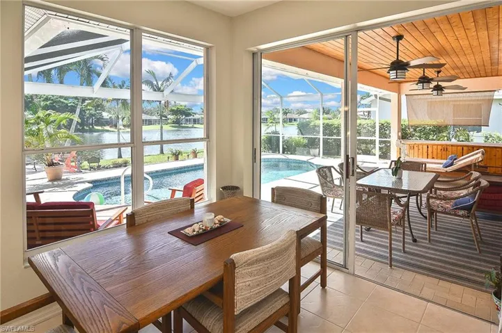 Dining room with a sunroom, a water view, light tile patterned flooring, and wooden ceiling