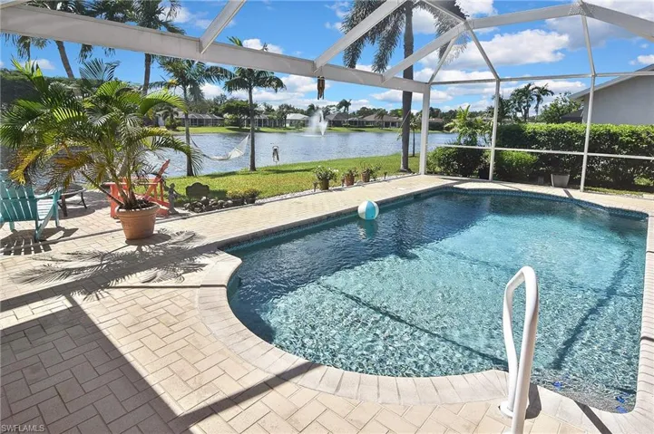 Outdoor pool with a water view, a patio area, a sunroom, glass enclosure, and a residential view