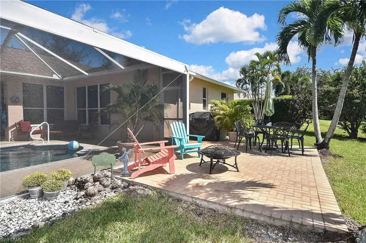 View of patio featuring a fire pit, a lanai, area for grilling, a sunroom, and an outdoor pool