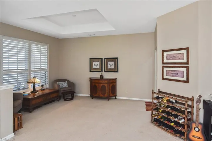 Living area with a tray ceiling and light colored carpet