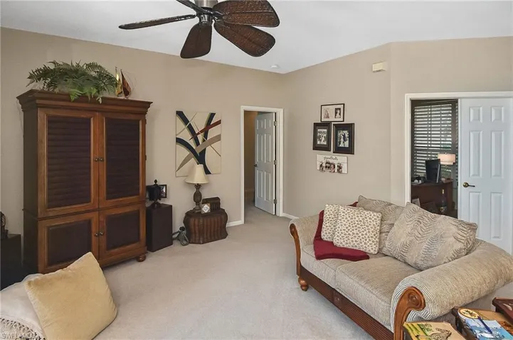 Carpeted living room with a ceiling fan and baseboards