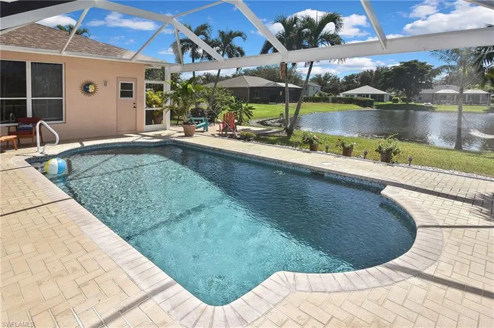 Outdoor pool featuring a patio, a sunroom, a water view, and glass enclosure