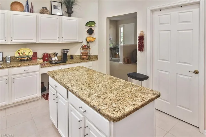 Kitchen featuring white cabinetry, light stone counters, light tile patterned floors, and a kitchen island