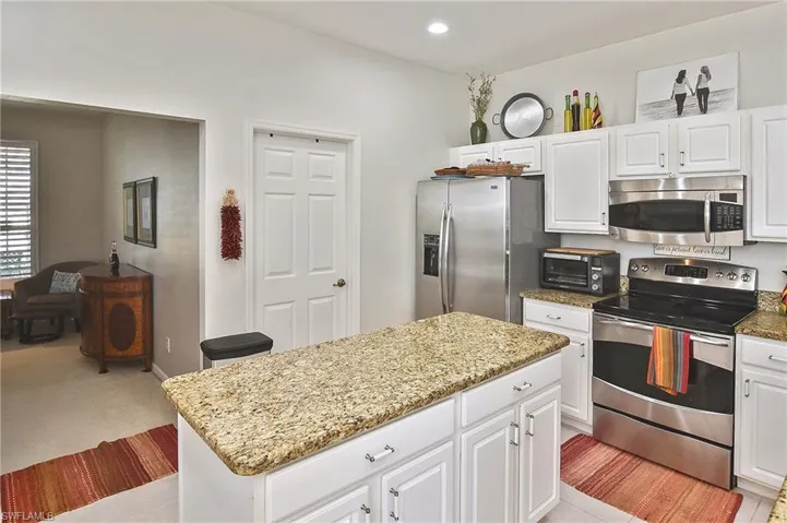 Kitchen featuring stainless steel appliances, white cabinetry, light stone counters, a kitchen island, and recessed lighting