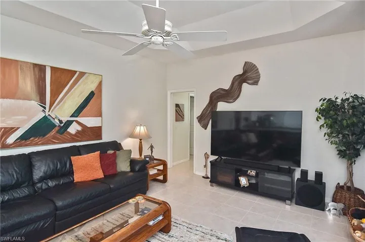 Living area with tile patterned floors and a ceiling fan