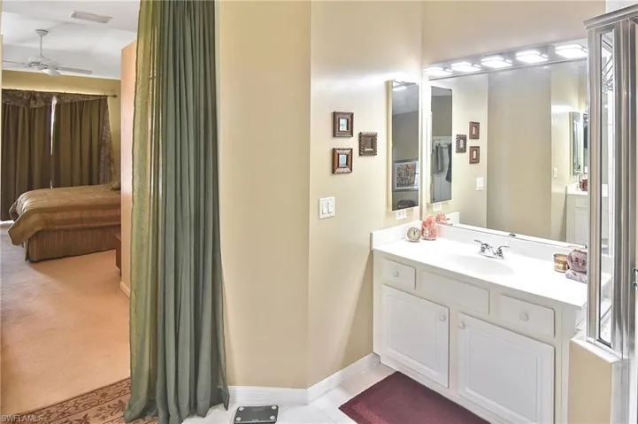 Ensuite bathroom with vanity, a ceiling fan, and light tile patterned floors