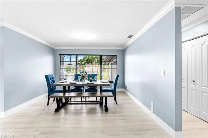 Dining area with ornamental molding and light wood-style flooring