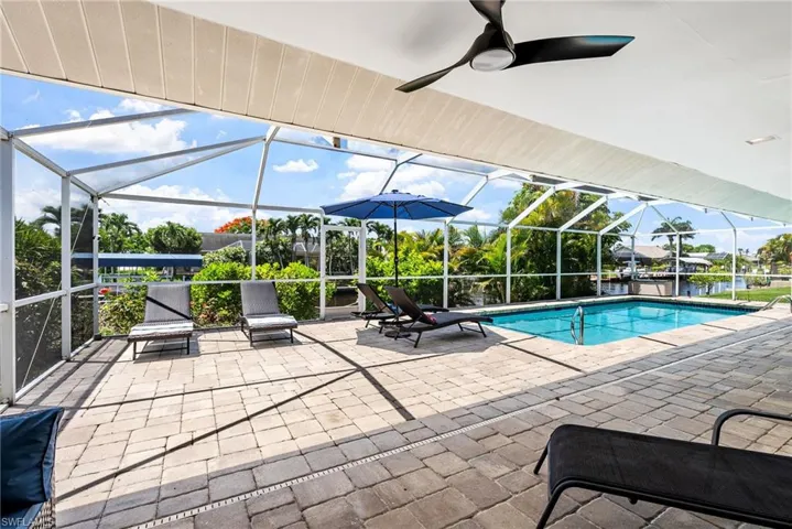 Outdoor pool with a patio area, glass enclosure, a sunroom, and a ceiling fan