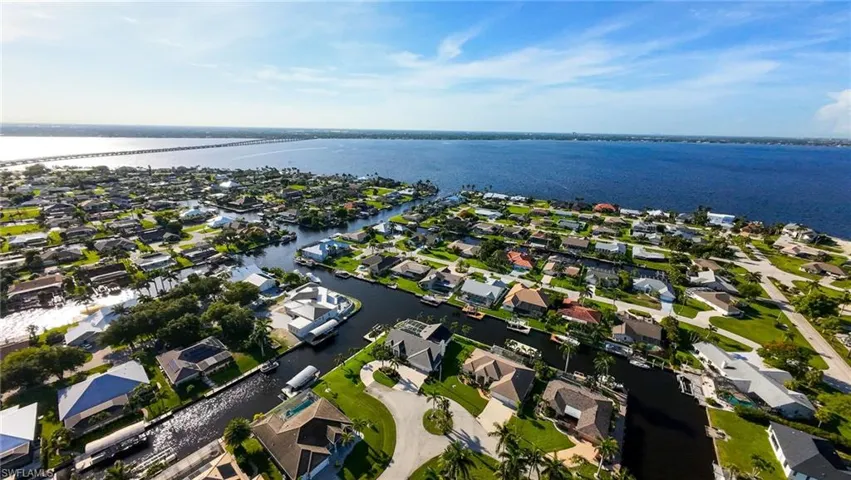 Aerial view of property and surrounding area featuring a nearby body of water and nearby suburban area