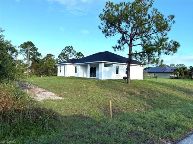 Rear view of property with a lawn and stucco siding
