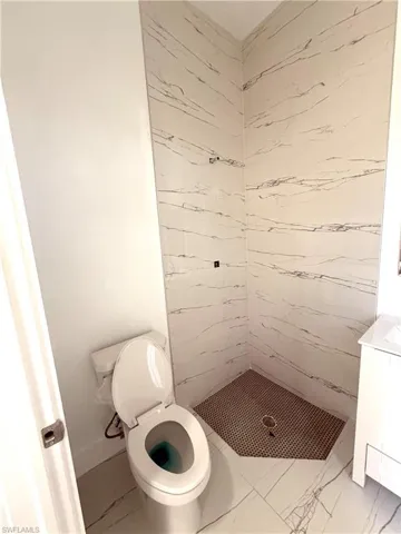 Full bathroom featuring a stall shower, vanity, and light marble finish floors