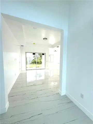 Unfurnished room featuring light marble finish floors and baseboards