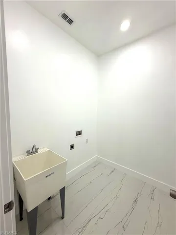 Laundry room with electric dryer hookup, light marble finish flooring, and recessed lighting
