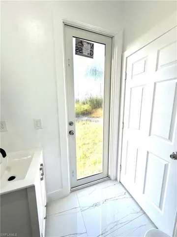Doorway to outside with marble finish floors and a sink