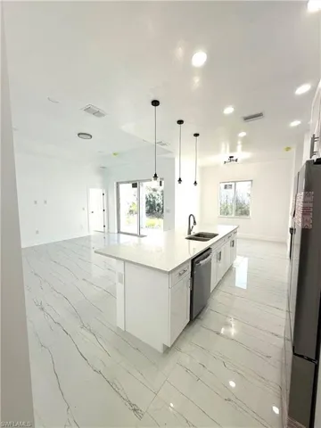 Kitchen with open floor plan, white cabinets, light marble finish floors, and recessed lighting