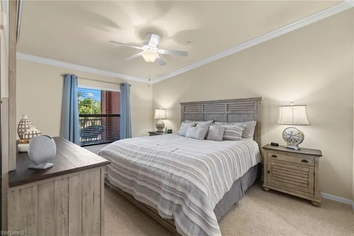 Bedroom featuring a ceiling fan, light colored carpet, baseboards, and ornamental molding