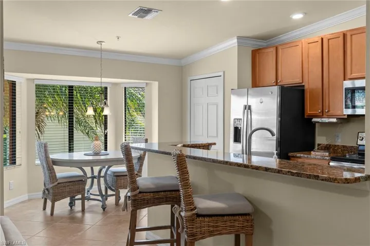 Kitchen with decorative light fixtures, a breakfast bar, ornamental molding, light tile patterned floors, and stainless steel appliances