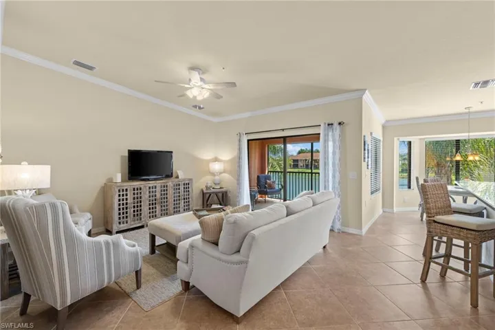 Living area with tile patterned floors, baseboards, visible vents, and ornamental molding