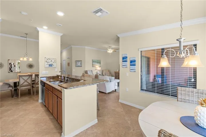 Kitchen featuring visible vents, dark stone counters, a sink, crown molding, and open floor plan