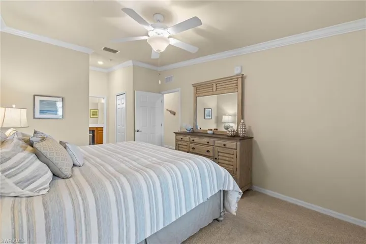 Bedroom featuring crown molding, baseboards, visible vents, and light carpet