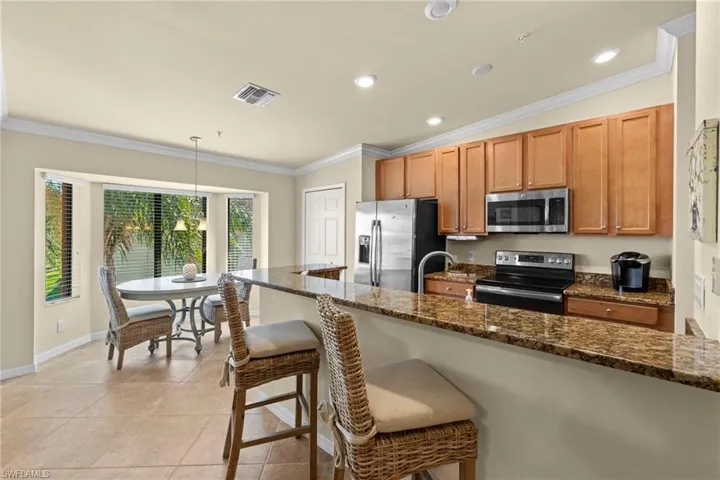 Kitchen featuring visible vents, crown molding, a breakfast bar, light tile patterned flooring, and stainless steel appliances