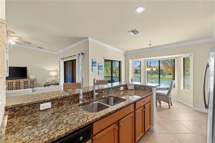 Kitchen with visible vents, brown cabinets, ornamental molding, a sink, and freestanding refrigerator