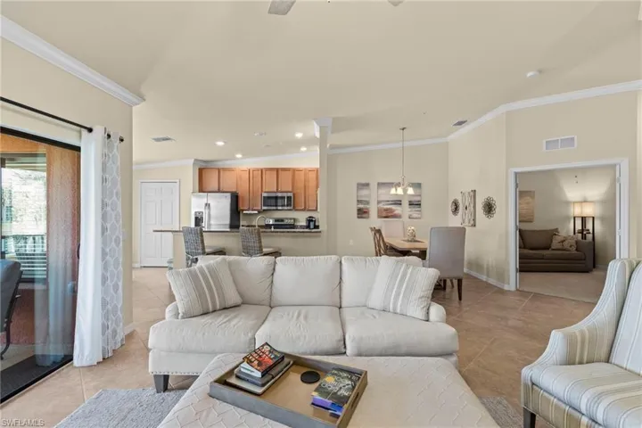 Living area featuring light tile patterned floors, visible vents, an inviting chandelier, and crown molding