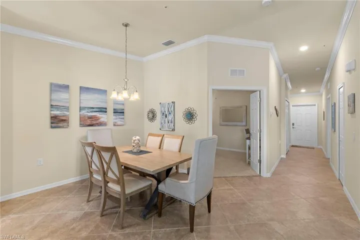 Dining space with a notable chandelier, visible vents, crown molding, and baseboards