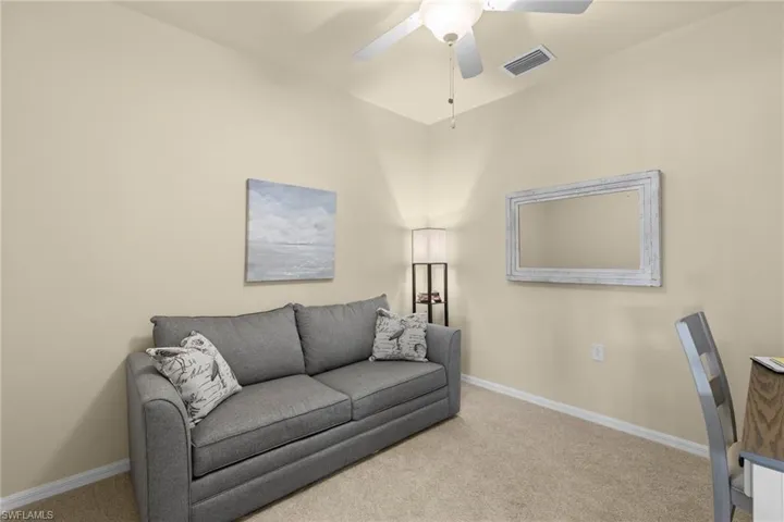 Living room with a ceiling fan, visible vents, carpet floors, and baseboards