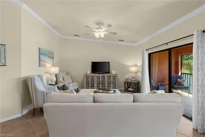 Tiled living room featuring visible vents, baseboards, a ceiling fan, and ornamental molding
