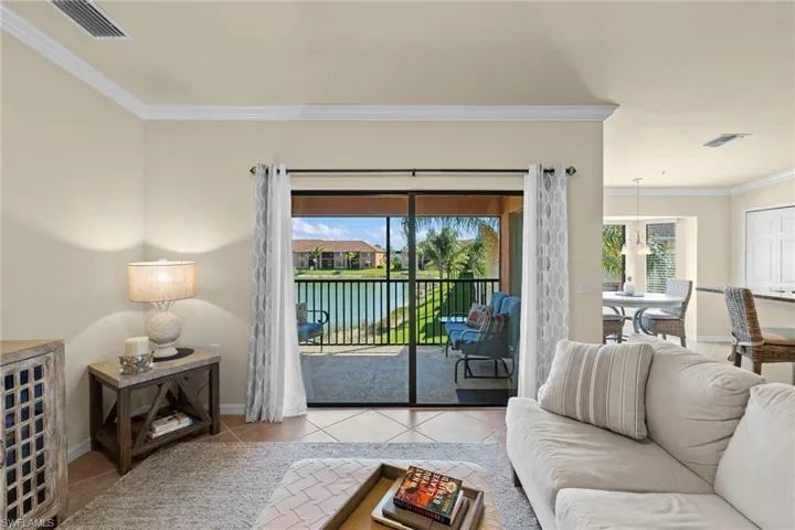 Tiled living room featuring visible vents, baseboards, and crown molding