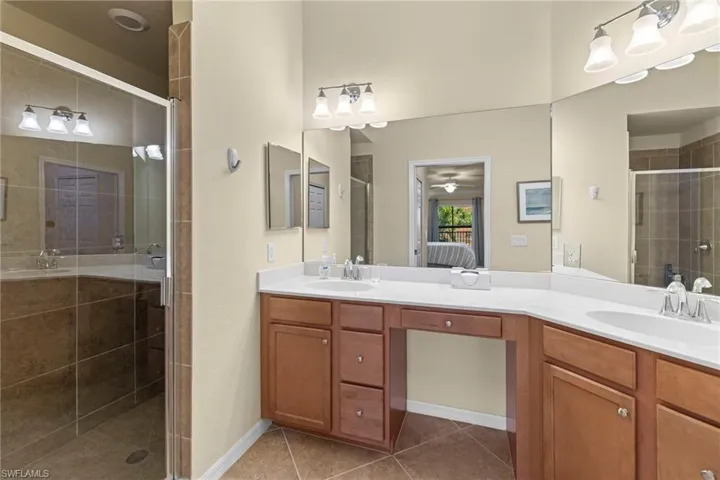 Ensuite bathroom featuring ensuite bath, a stall shower, tile patterned floors, and a sink