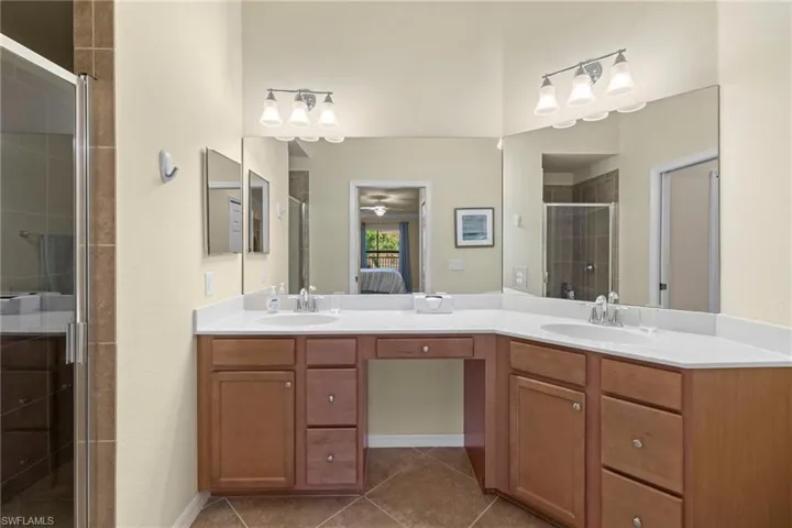 Full bath featuring ensuite bath, a shower stall, double vanity, and a sink
