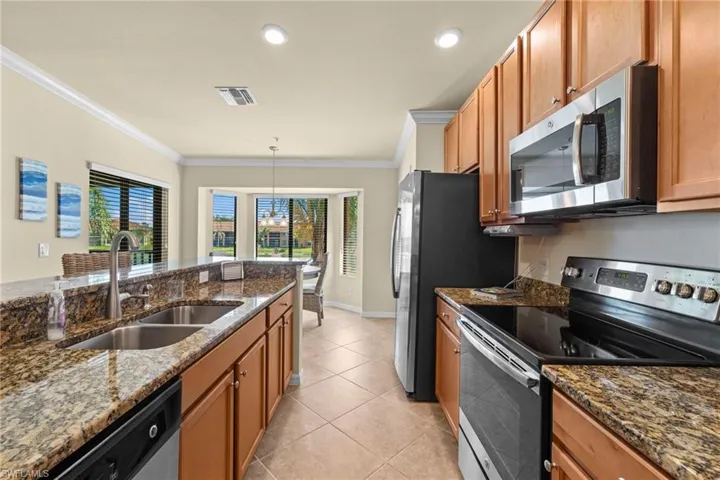 Kitchen with visible vents, appliances with stainless steel finishes, crown molding, and a sink