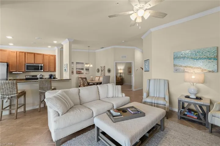 Living area with recessed lighting, baseboards, light tile patterned flooring, and ceiling fan with notable chandelier