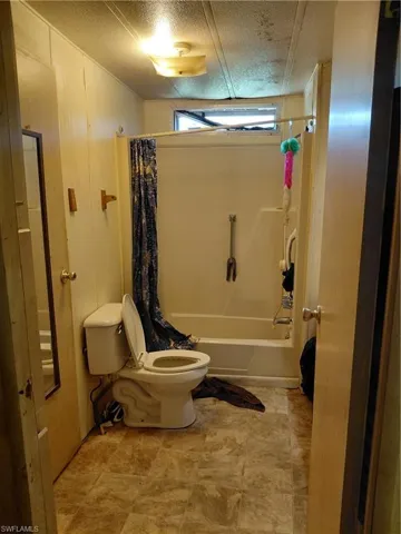 Full bath featuring shower / bath combo and a textured ceiling