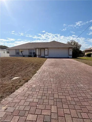 Ranch-style home featuring decorative driveway, a garage, and covered porch
