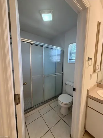 Full bath with vanity, light tile patterned floors, and a stall shower