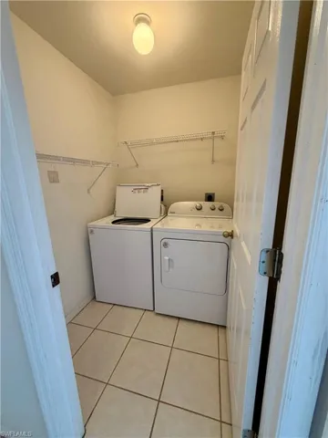 Laundry room with light tile patterned floors and washing machine and dryer