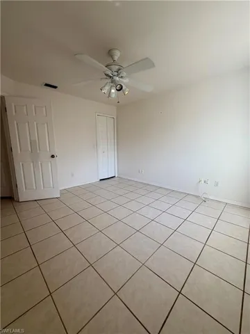 Unfurnished bedroom featuring light tile patterned flooring, a ceiling fan, and a closet