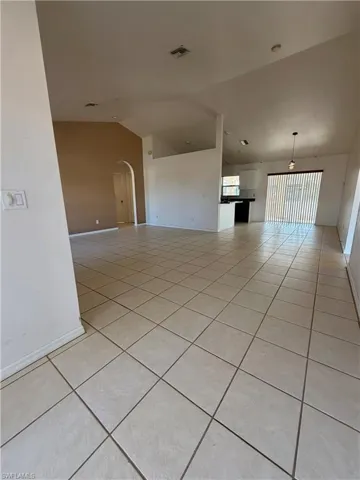 Unfurnished room with light tile patterned flooring, vaulted ceiling, and arched walkways