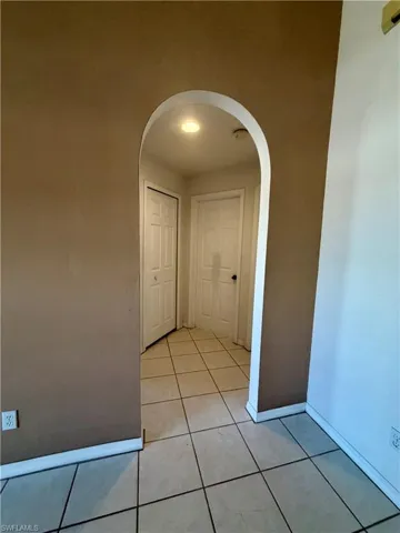 Hall featuring arched walkways and light tile patterned flooring